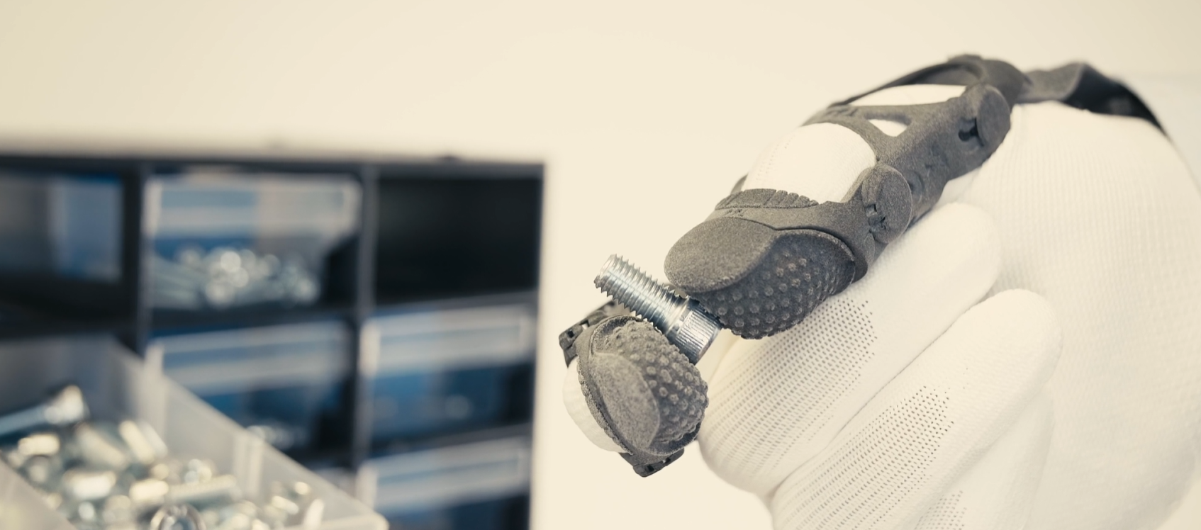 Close-up of a hand wearing ARTUS holding an industrial screw